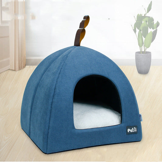 Blue pet bed with a white cushion on a wooden floor, featuring a plant in the background.